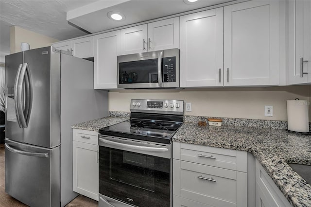 6053 11th Ave, New Port Richey, FL 34653 - kitchen featuring appliances with stainless steel finishes, white cabinetry, light stone countertops, wood finished floors, and recessed lighting