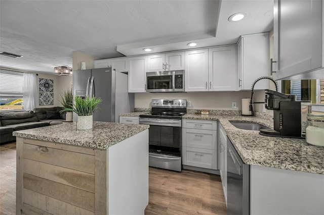 6053 11th Ave, New Port Richey, FL 34653 - kitchen featuring appliances with stainless steel finishes, recessed lighting, wood finished floors, light stone counters, and a kitchen island