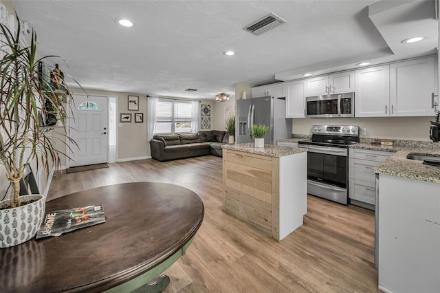 6053 11th Ave, New Port Richey, FL 34653 - kitchen with appliances with stainless steel finishes, a center island, light wood finished floors, recessed lighting, and light stone countertops