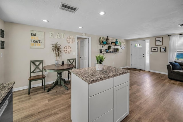 6053 11th Ave, New Port Richey, FL 34653 - kitchen featuring light wood-type flooring, recessed lighting, dark stone countertops, white cabinetry, and a center island