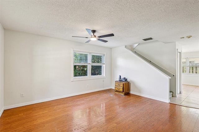 808 Franklin Cir, Palm Harbor, FL 34683 - unfurnished living room featuring a ceiling fan, light wood-style floors, a textured ceiling, and stairway