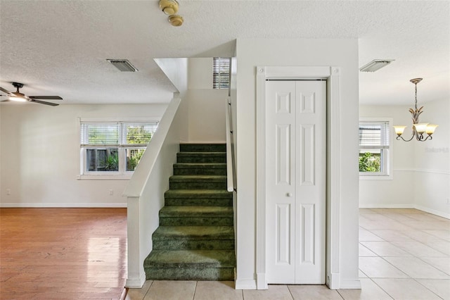 808 Franklin Cir, Palm Harbor, FL 34683 - stairway featuring a textured ceiling, a chandelier, a ceiling fan, and tile patterned flooring