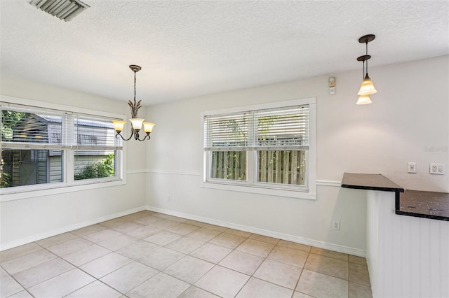 808 Franklin Cir, Palm Harbor, FL 34683 - unfurnished dining area featuring plenty of natural light, a chandelier, light tile patterned flooring, and a textured ceiling