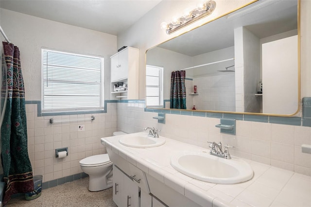 11830 86th Ave, Seminole, FL 33772 - bathroom with double vanity, a shower with shower curtain, tile walls, a wainscoted wall, and speckle patterned floor