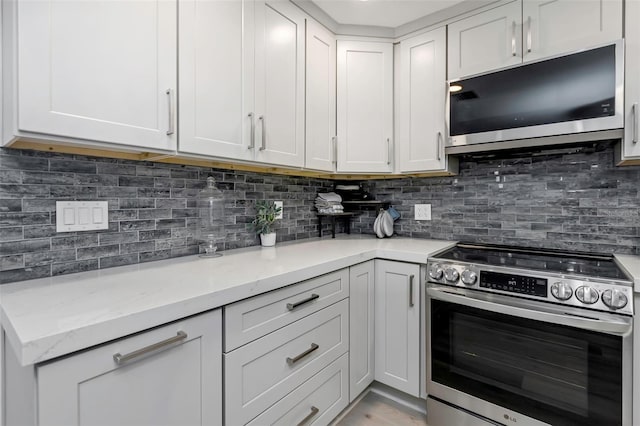 2630 St Josephs Dr W, Dunedin, FL 34698 - kitchen featuring appliances with stainless steel finishes, light stone countertops, backsplash, and white cabinets