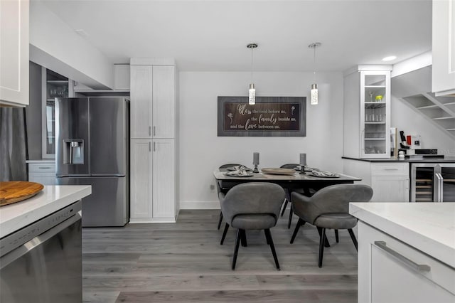 2630 St Josephs Dr W, Dunedin, FL 34698 - kitchen featuring appliances with stainless steel finishes, beverage cooler, white cabinets, light wood-type flooring, and decorative light fixtures