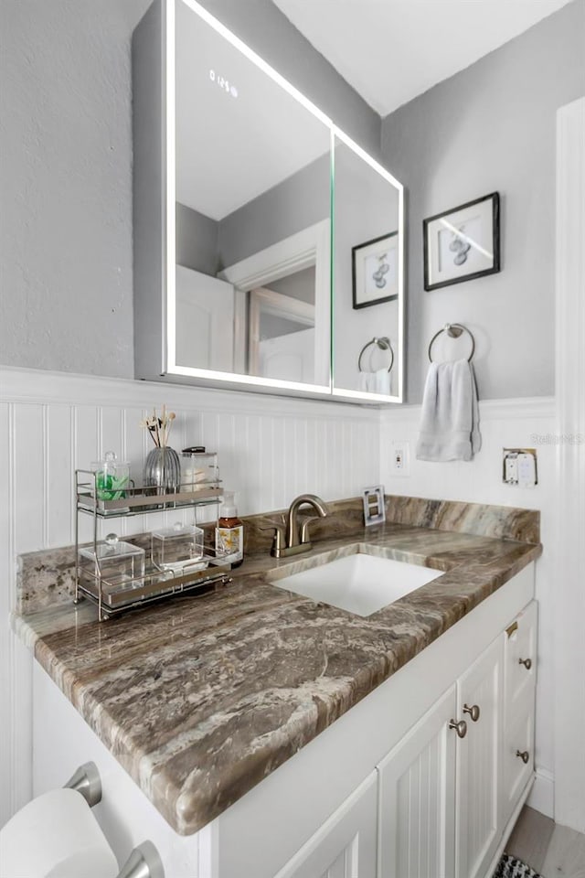 2630 St Josephs Dr W, Dunedin, FL 34698 - bathroom with vanity, wainscoting, and a decorative wall