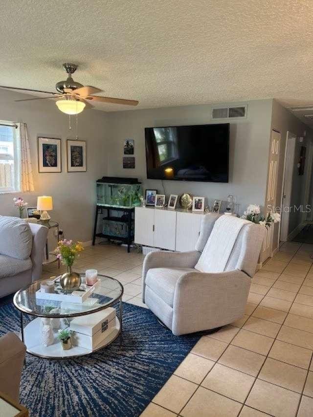 4487 Anderson Rd, Orlando, FL 32812 - tiled living room featuring a textured ceiling and a ceiling fan