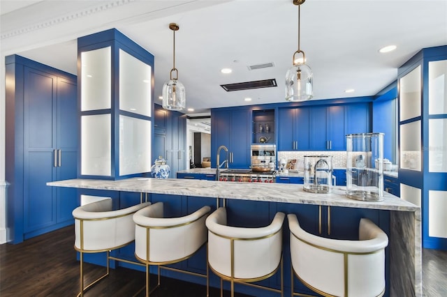450 Knights Run Ave Unit 2004, Tampa, FL 33602 - kitchen featuring dark wood-type flooring, blue cabinetry, glass insert cabinets, a large island with sink, and a breakfast bar area