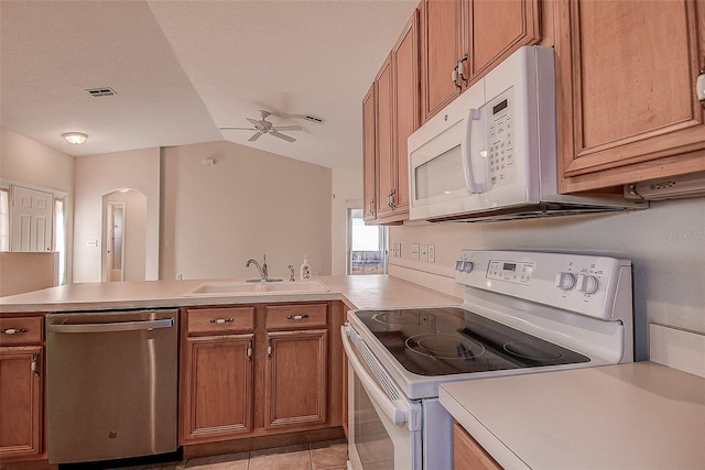29417 Caddyshack Ln, San Antonio, FL 33576 - kitchen with white appliances, a peninsula, brown cabinetry, a ceiling fan, and vaulted ceiling
