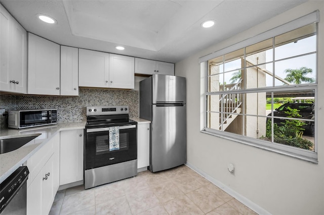 970 Virginia St Unit 109, Dunedin, FL 34698 - kitchen with stainless steel appliances, decorative backsplash, white cabinets, light tile patterned floors, and recessed lighting