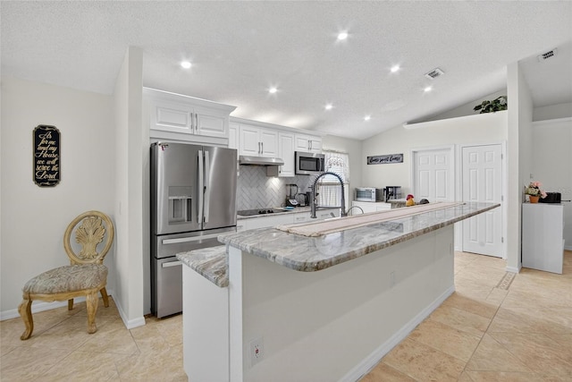 13040 Waterbourne Dr, Gibsonton, FL 33534 - kitchen with stainless steel appliances, backsplash, white cabinets, a center island with sink, and light stone countertops