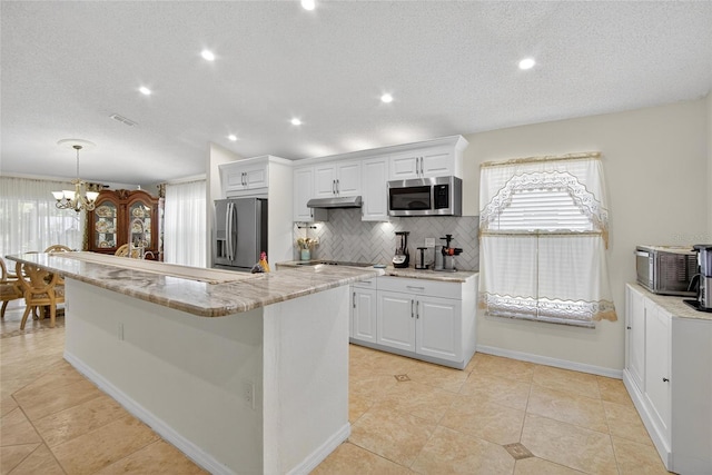 13040 Waterbourne Dr, Gibsonton, FL 33534 - kitchen featuring stainless steel appliances, tasteful backsplash, white cabinetry, a chandelier, and a textured ceiling