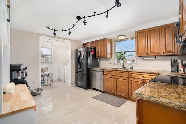 7510 Tyson Dr, Port Richey, FL 34668 - kitchen with stainless steel dishwasher, freestanding refrigerator, brown cabinetry, backsplash, and rail lighting