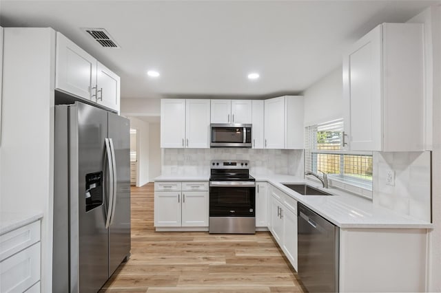 4236 Woodtrail Blvd, New Port Richey, FL 34653 - kitchen featuring stainless steel appliances, light wood-style floors, white cabinets, light countertops, and decorative backsplash