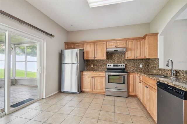 501 Royal Ridge St, Valrico, FL 33594 - kitchen with stainless steel appliances, under cabinet range hood, backsplash, arched walkways, and light tile patterned floors