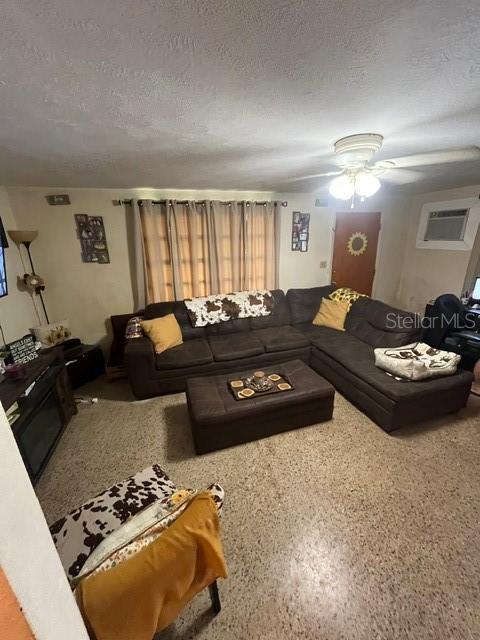8946 Dream Way, Largo, FL 33773 - living area featuring an AC wall unit, a textured ceiling, and ceiling fan