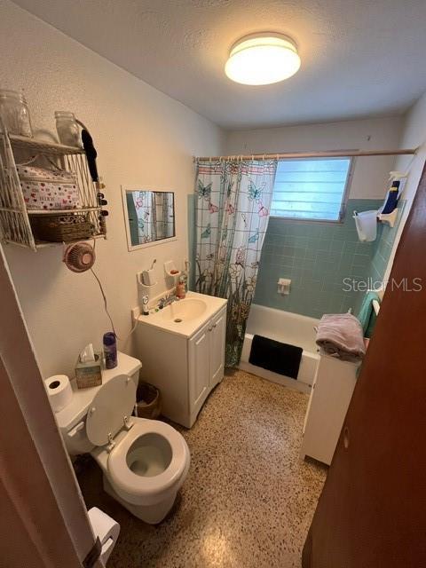8946 Dream Way, Largo, FL 33773 - bathroom with shower / bath combination with curtain, vanity, and speckle patterned floor