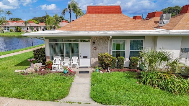 4360 Tahitian Gardens Cir Unit H, Holiday, FL 34691 - view of front of property with a front yard, a water view, a shingled roof, and stucco siding