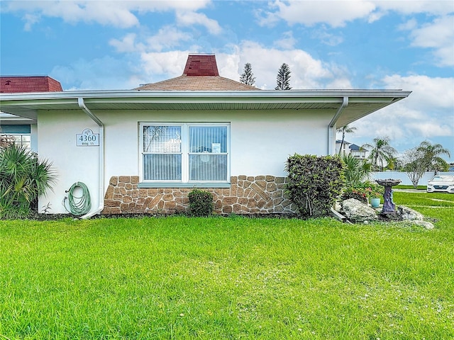 4360 Tahitian Gardens Cir Unit H, Holiday, FL 34691 - view of property exterior featuring stucco siding, a lawn, a chimney, and stone siding