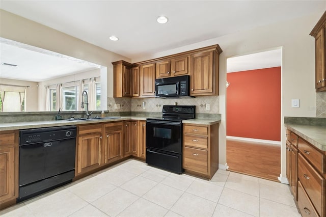 4514 John Moore Rd, Brandon, FL 33511 - kitchen with black appliances, tasteful backsplash, brown cabinets, light tile patterned flooring, and recessed lighting
