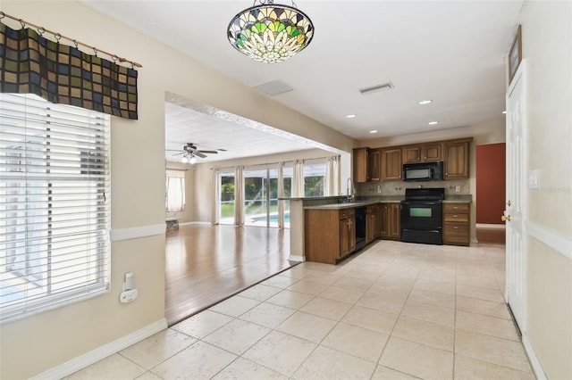 4514 John Moore Rd, Brandon, FL 33511 - kitchen featuring black appliances, brown cabinets, light tile patterned flooring, and recessed lighting