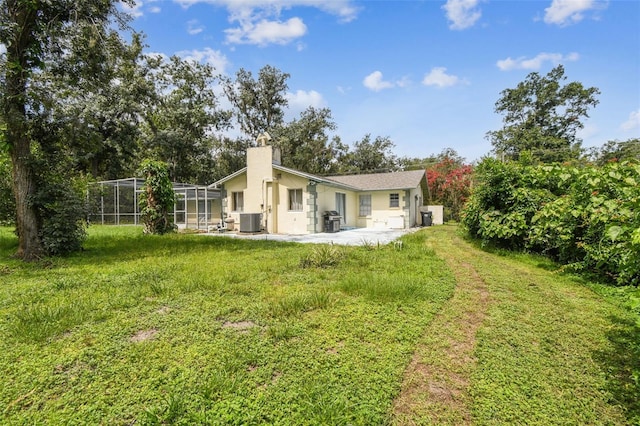 4514 John Moore Rd, Brandon, FL 33511 - back of property with a chimney, a patio, stucco siding, a lanai, and a lawn