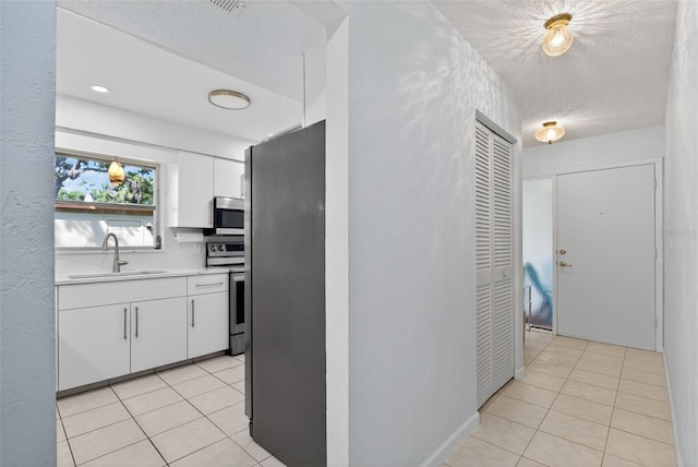 7051 Bright Creek Dr Unit 6, Sarasota, FL 34231 - kitchen with stainless steel appliances, light countertops, light tile patterned floors, white cabinetry, and a textured ceiling