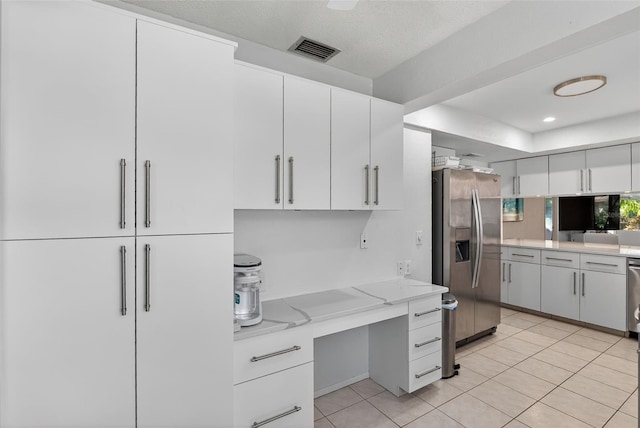 7051 Bright Creek Dr Unit 6, Sarasota, FL 34231 - kitchen featuring stainless steel refrigerator with ice dispenser, white cabinets, light tile patterned floors, light stone counters, and built in desk