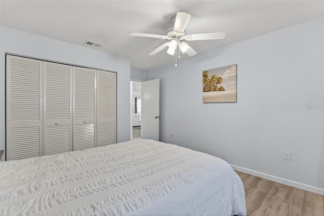 7051 Bright Creek Dr Unit 6, Sarasota, FL 34231 - bedroom with light wood-style flooring, a closet, a textured ceiling, and ceiling fan