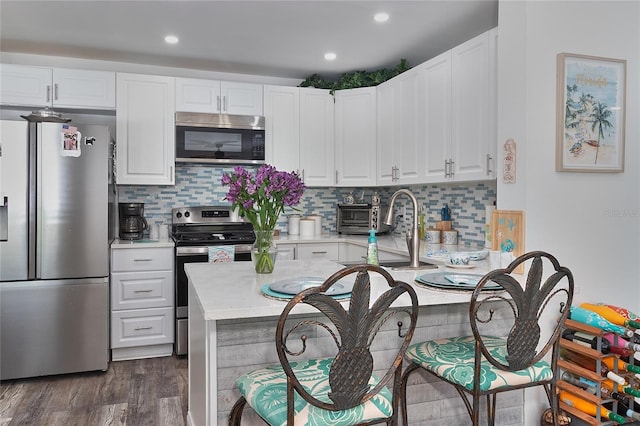 700 Starkey Rd Unit 1124, Largo, FL 33771 - kitchen featuring stainless steel appliances, white cabinets, dark wood-style floors, backsplash, and recessed lighting