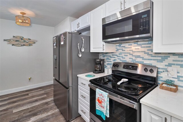 700 Starkey Rd Unit 1124, Largo, FL 33771 - kitchen with appliances with stainless steel finishes, light countertops, dark wood-type flooring, backsplash, and white cabinetry