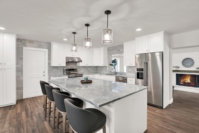 6000 115th Ln, Seminole, FL 33772 - kitchen with stainless steel appliances, a kitchen island, under cabinet range hood, dark wood-style flooring, and recessed lighting