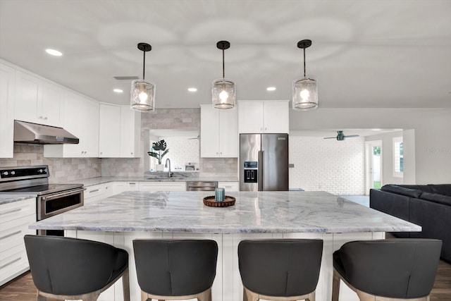 6000 115th Ln, Seminole, FL 33772 - kitchen with stainless steel appliances, under cabinet range hood, backsplash, open floor plan, and a center island