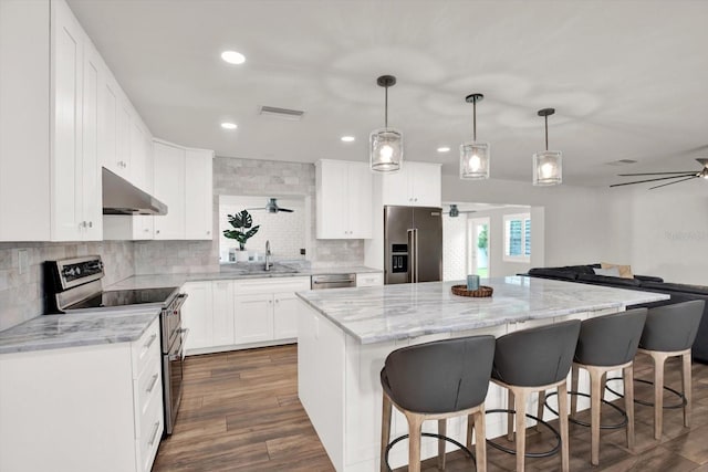 6000 115th Ln, Seminole, FL 33772 - kitchen with stainless steel appliances, range hood, a ceiling fan, a kitchen island, and decorative backsplash