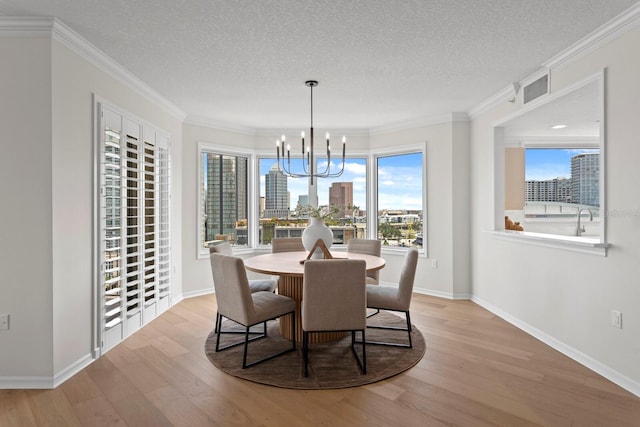 371 Channelside Walk Way Unit 1104, Tampa, FL 33602 - dining space featuring a chandelier, light wood-style flooring, a textured ceiling, healthy amount of natural light, and crown molding