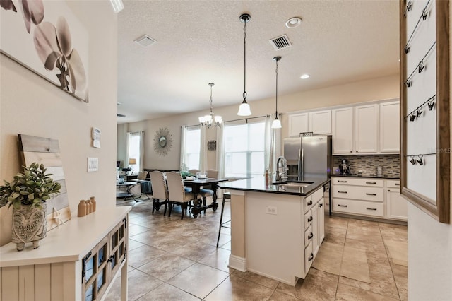 6934 Old Benton Dr, Apollo Beach, FL 33572 - kitchen featuring dark countertops, tasteful backsplash, white cabinets, a kitchen bar, and a kitchen island with sink
