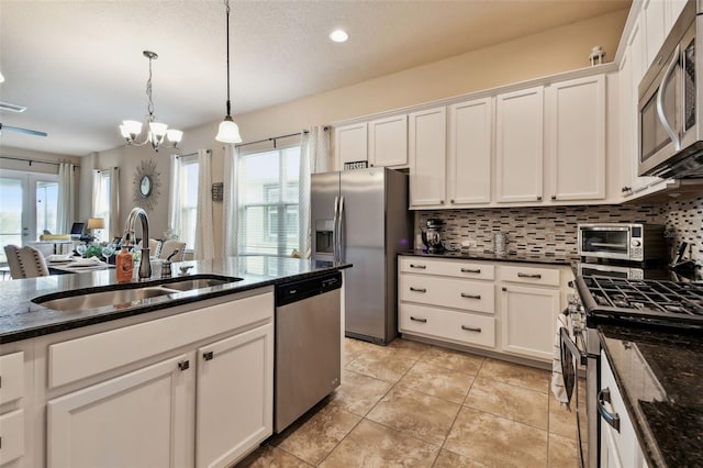 6934 Old Benton Dr, Apollo Beach, FL 33572 - kitchen with stainless steel appliances, decorative backsplash, white cabinets, a chandelier, and decorative light fixtures