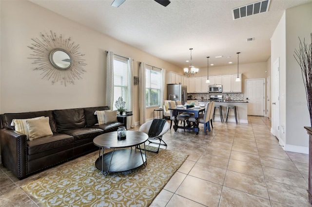 6934 Old Benton Dr, Apollo Beach, FL 33572 - living area with light tile patterned floors, a textured ceiling, a ceiling fan, and a chandelier