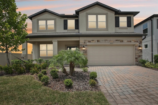33157 Rosewood Bark Way, Wesley Chapel, FL 33545 - view of front of home with stucco siding, stone siding, an attached garage, decorative driveway, and covered porch