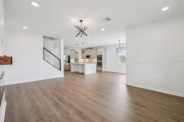 33157 Rosewood Bark Way, Wesley Chapel, FL 33545 - unfurnished living room featuring a chandelier, recessed lighting, and dark wood-style flooring