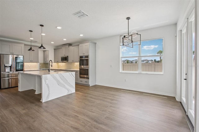 33157 Rosewood Bark Way, Wesley Chapel, FL 33545 - kitchen with appliances with stainless steel finishes, gray cabinetry, decorative backsplash, a chandelier, and recessed lighting