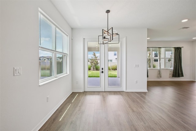 33157 Rosewood Bark Way, Wesley Chapel, FL 33545 - unfurnished dining area featuring a chandelier, wood finished floors, french doors, and recessed lighting