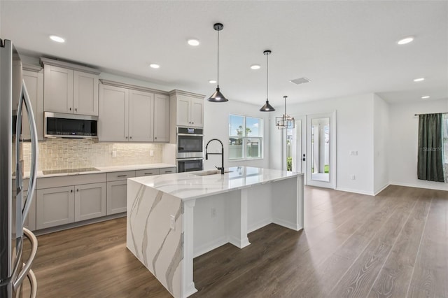 33157 Rosewood Bark Way, Wesley Chapel, FL 33545 - kitchen featuring appliances with stainless steel finishes, gray cabinets, backsplash, light stone counters, and recessed lighting