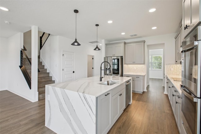 33157 Rosewood Bark Way, Wesley Chapel, FL 33545 - kitchen featuring stainless steel appliances, decorative backsplash, wood finished floors, gray cabinets, and recessed lighting