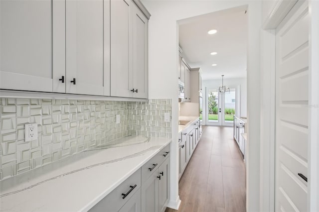 33157 Rosewood Bark Way, Wesley Chapel, FL 33545 - kitchen featuring light stone counters, decorative backsplash, recessed lighting, light wood-type flooring, and hanging light fixtures