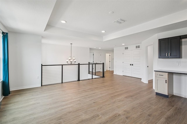 33157 Rosewood Bark Way, Wesley Chapel, FL 33545 - unfurnished living room featuring a chandelier, a tray ceiling, recessed lighting, and light wood-type flooring