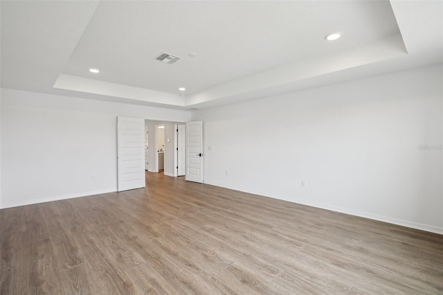 33157 Rosewood Bark Way, Wesley Chapel, FL 33545 - spare room with a tray ceiling, recessed lighting, and wood finished floors
