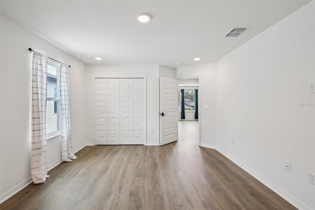 33157 Rosewood Bark Way, Wesley Chapel, FL 33545 - unfurnished bedroom featuring wood finished floors, a closet, and recessed lighting
