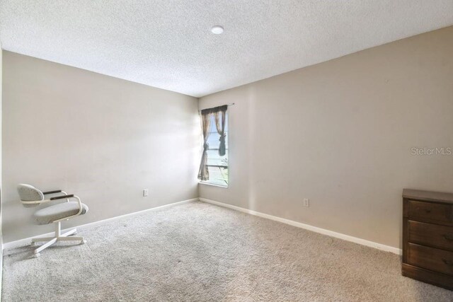 8030 San Bernardino Dr, Port Richey, FL 34668 - carpeted spare room with a textured ceiling and baseboards